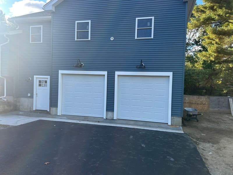 White flush dual garage doors on blue-gray new construction home